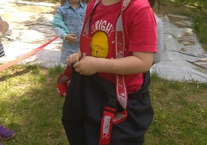 Zdjęcie przedstawia zadowolonego chłopca, który ubrał się w spodnie strażackie